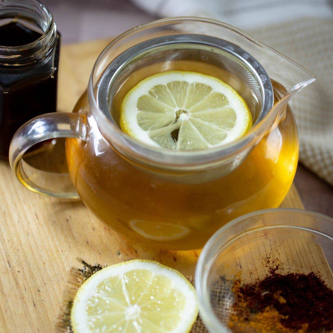 lemon ginger green tea in a tea cup with a lemon wedge