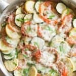 One pan fresh zucchini tomato eggplant baked in a large skillet and topped with fresh mozzarella cheese that has melted over the fresh veggies