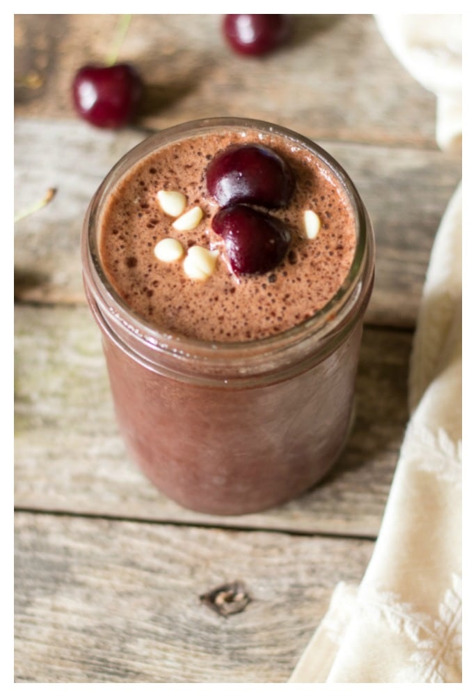 Cherry chocolate smoothie in a mason jar topped with diced cherries.