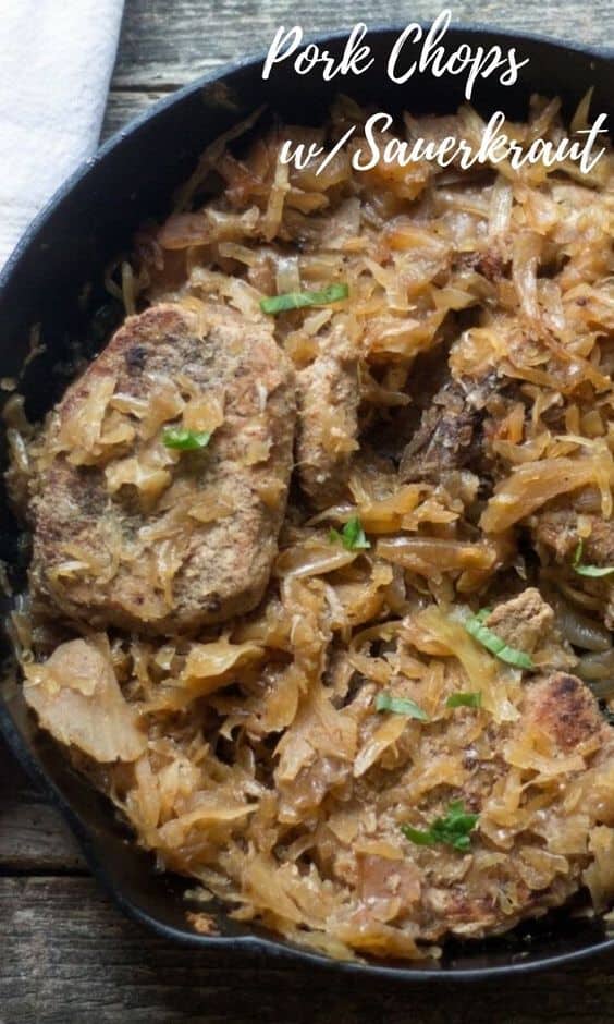 cast iron pan with baked pork chops topped with sauerkraut