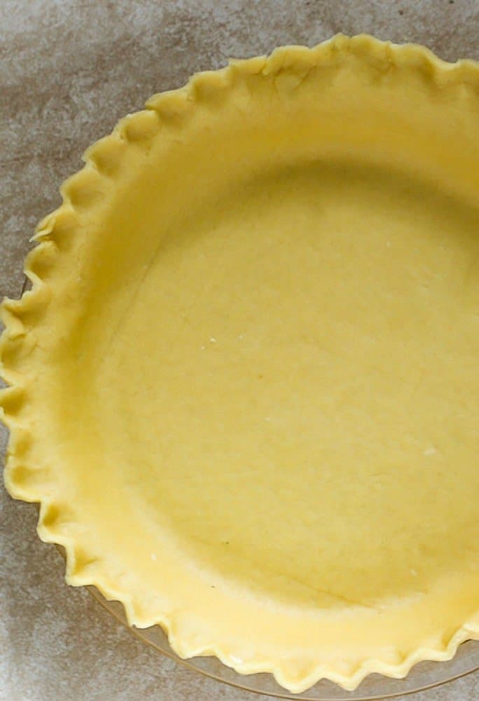 An overhead shot of a butter based flaky pie crust with crimped edges. Ready to either bake or fill with a tasty filling.