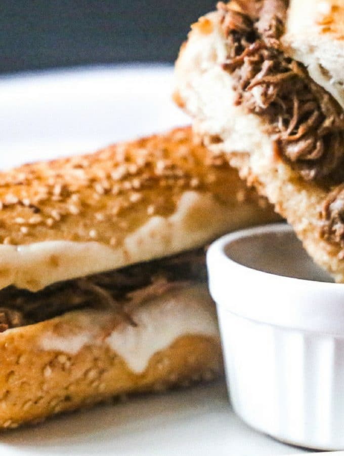 warm slow cooker french dip sandwich with melted provolone cheese dipped into a au jus sauce