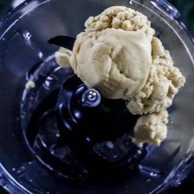 A food processor with the all butter pie dough that has formed a dough in the steps to How to Make a Homemade Flaky PIe Dough