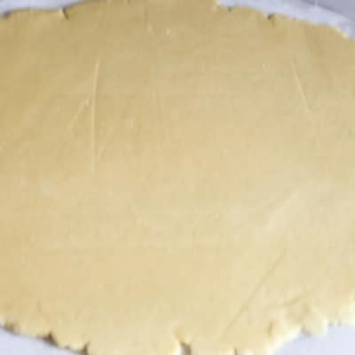 An aerial view of a homemade pie crust from scratch that is an all butter crust that has been rolled out on a floured pie sheet form.