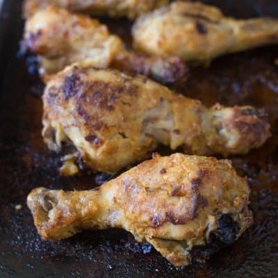 Side view of oven fried chicken drumsticks on a baking sheet