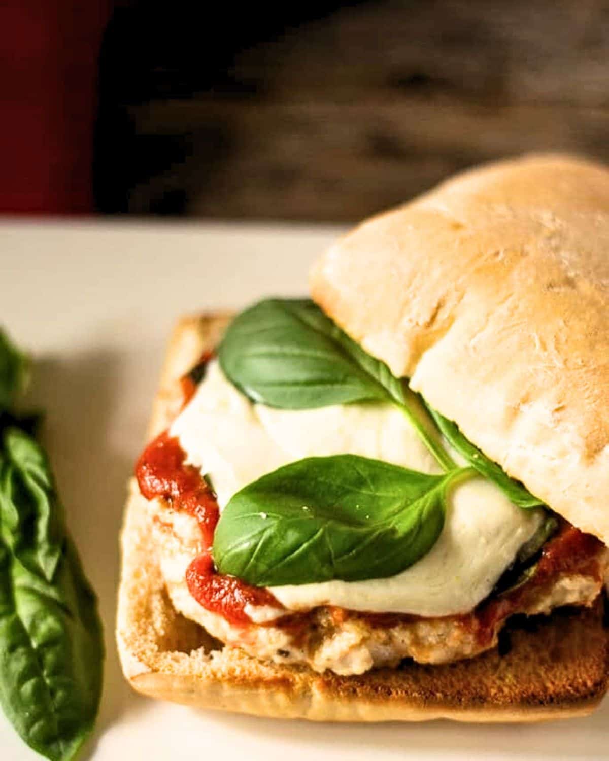 Chicken parm burger on a hard roll with fresh basil and fresh mozzarella. 