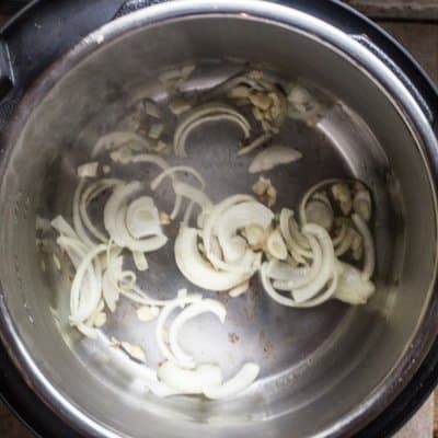 An overview of chopped onions and minced garlic sauteeing to make easy homemade BBQ sauce.