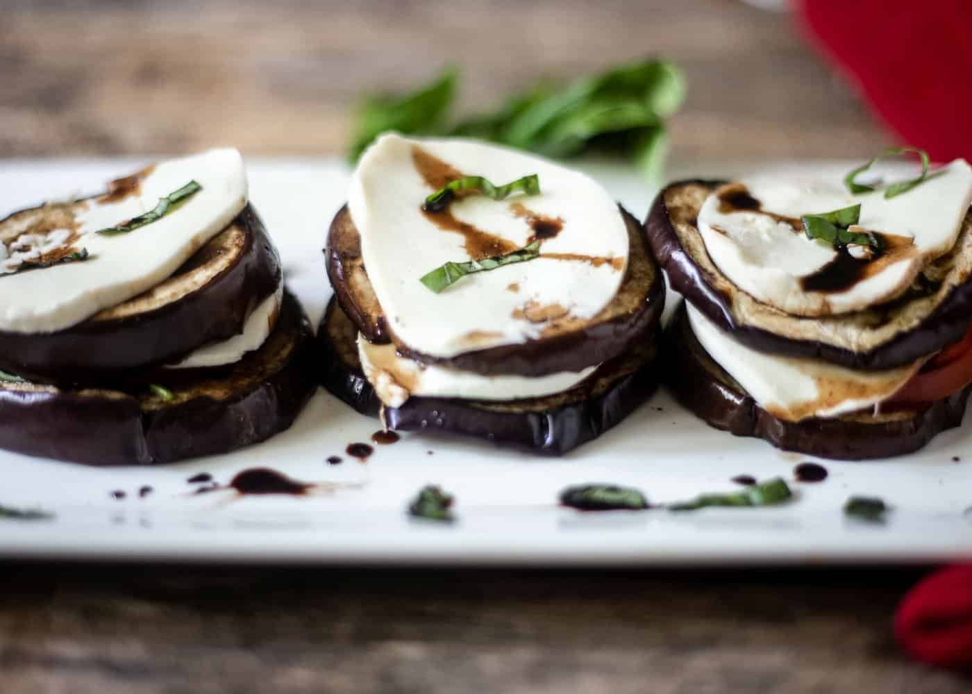 Grilled eggplant, tomato, basil, and fresh mozzarella stacked with a balsamic glaze drizzled on the eggplant stacks.