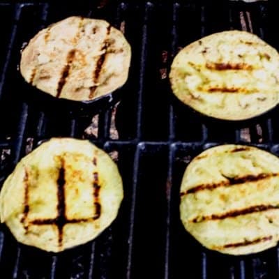 Eggplant that has been seasoned and brushed with olive oil is being grilled to make an awesome grilled eggplant recipe.
