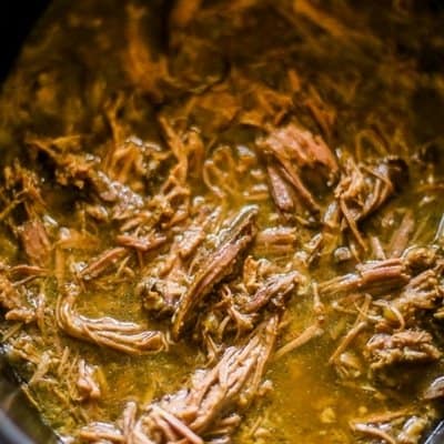 An overhead view of shredded beef in a slow cooker for slow cooker french dip sandwiches.