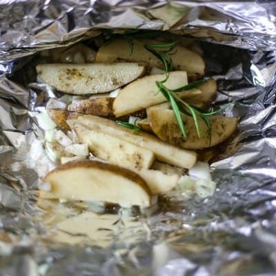 Potato slices in aluminum foil ready to be grilled to make camp fire potatoes