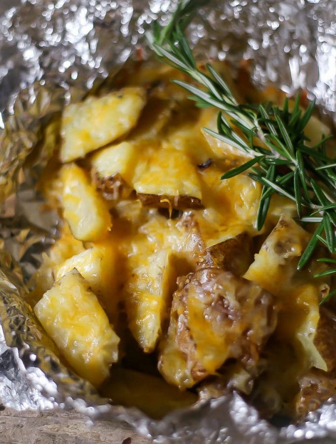 Cheesy foil potatoes that hav been roasted on the grill and ready to be enjoyed
