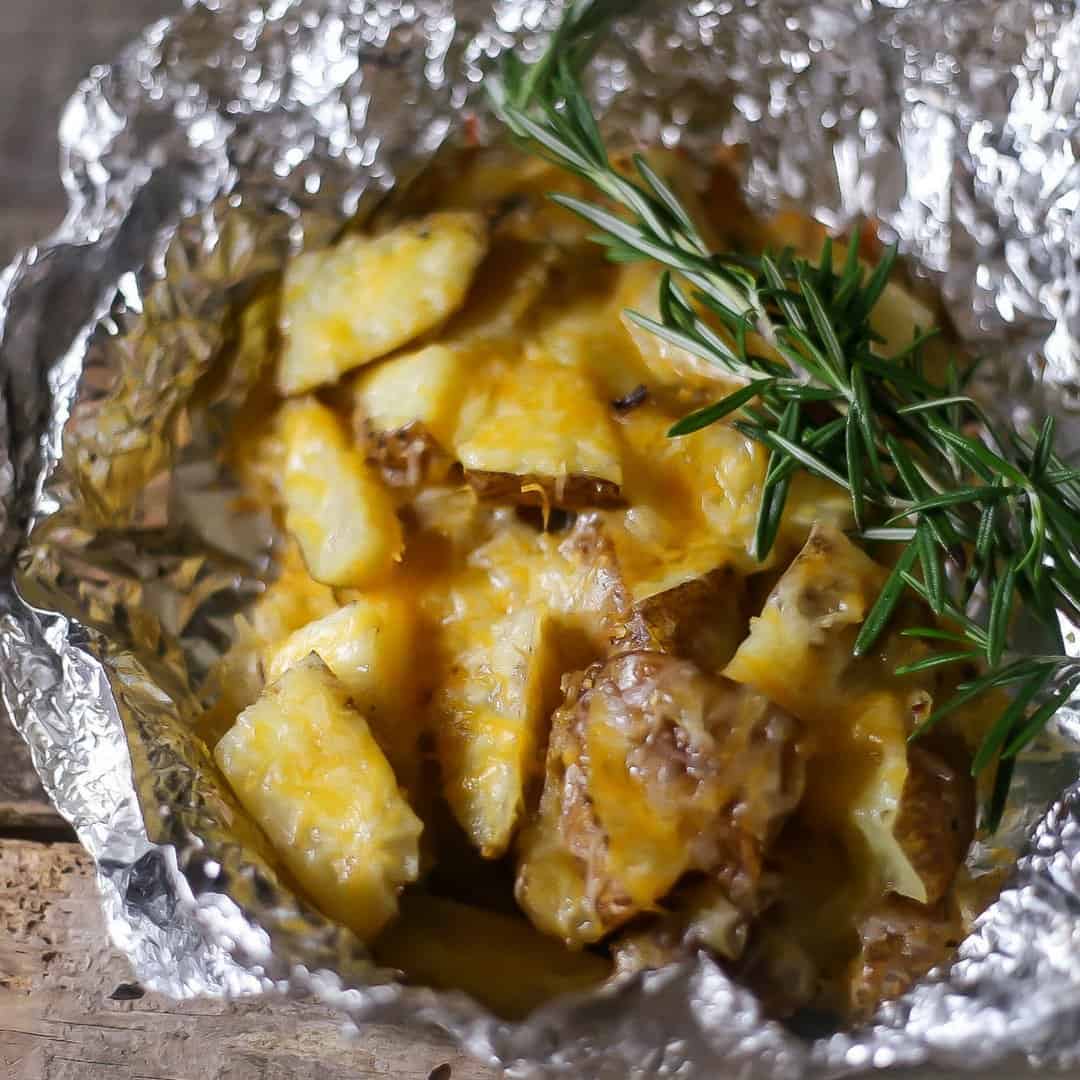 Cheesy foil potatoes that hav been roasted on the grill and ready to be enjoyed