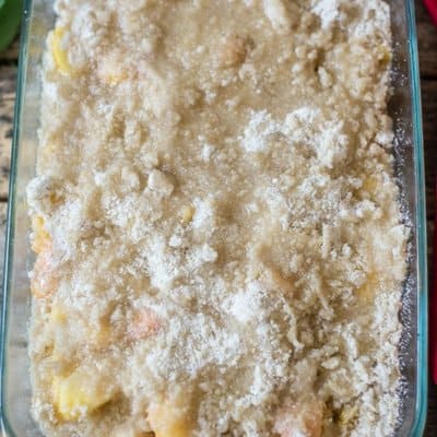 Peach crumble in a baking pan with a delicious crumble topping ready to be baked in the oven.
