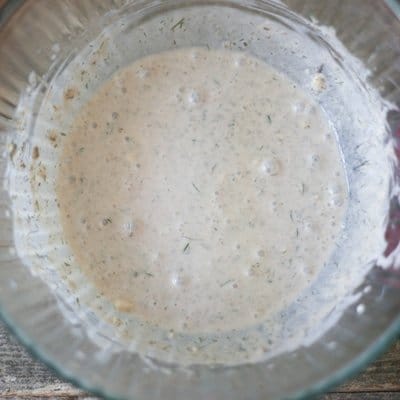 Gyro marinade made of yogurt, lime juice, dill and seasonings in a glass bowl.