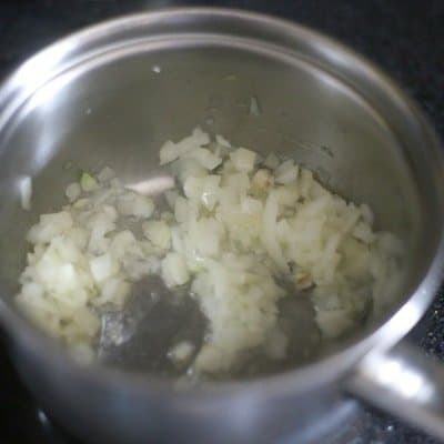 Preparing a teriyaki marinade in a silver saucepan beginning with sauteing onions and garlic in a little olive oil