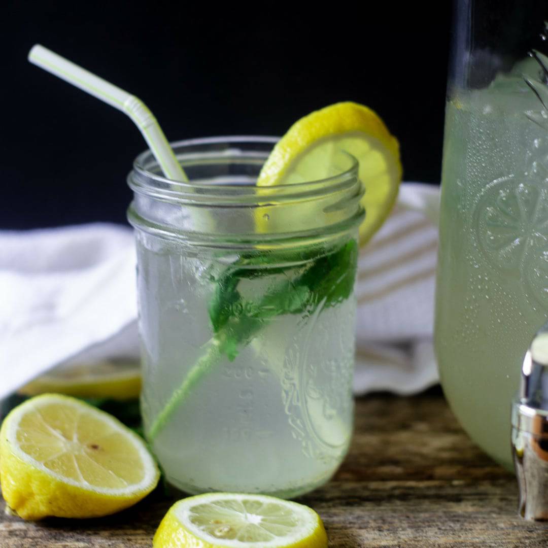 Thirst quenching mint ginger lemonade with mint and a lemon wedge on a wooden table ready to be served!