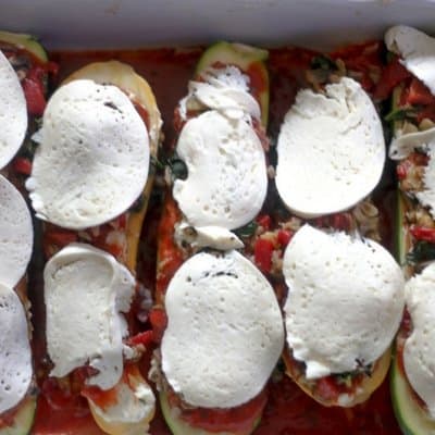 Over head photo of vegetable stuffed zucchini topped with fresh mozzarella waiting to be baked to cheesy goodness