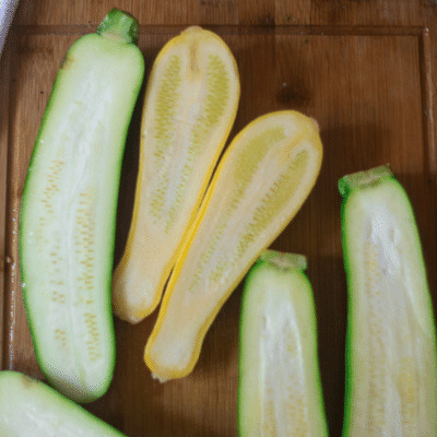 Zucchini has been sliced on a cutting board in half to make vegetable lasagna stuffed zucchini