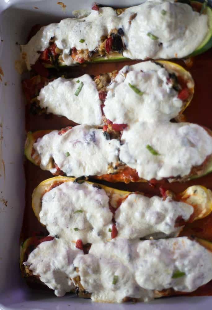 An overhead view of vegetable lasagna stuffed zucchini boats that have been baked and topped with fresh mozzarella cheese