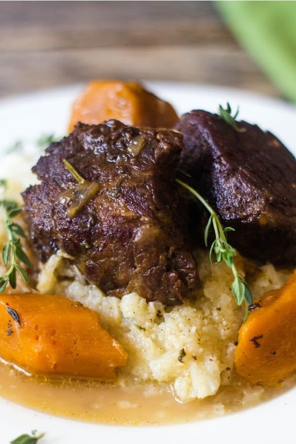 Beer Braised Short Ribs made in the Instant Pot topping mashed cauliflower and carrots.