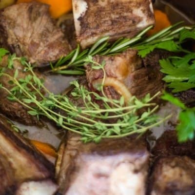 An instant pot filled with beef short ribs with carrots, onions, garlic, Guinness beer, beef stock, garlic, and herbs that will be quickly cooked to make beer braised beef short ribs