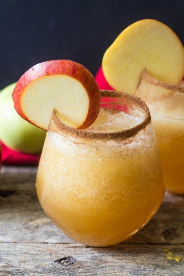 Caramel apple vodka smoothie in a clear glass with cinnamon sugar around the rim of the glass and an apple wedge in the rim of glass for garnish.