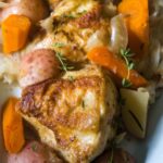 Hard cider braised chicken cabbage potatoes, fennel, apples, carrots on a platter.
