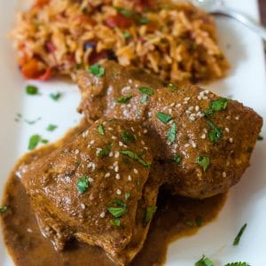 Chicken breasts with a mole sauce topped with toasted sesame seeds, pepitas, and chopped cilantro.