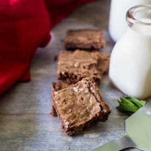 Chewy coconut oil brownies with a cold glass of milk in a dairy jar to its side.