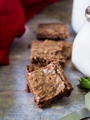 Chewy coconut oil brownies with a cold glass of milk in a dairy jar to its side.