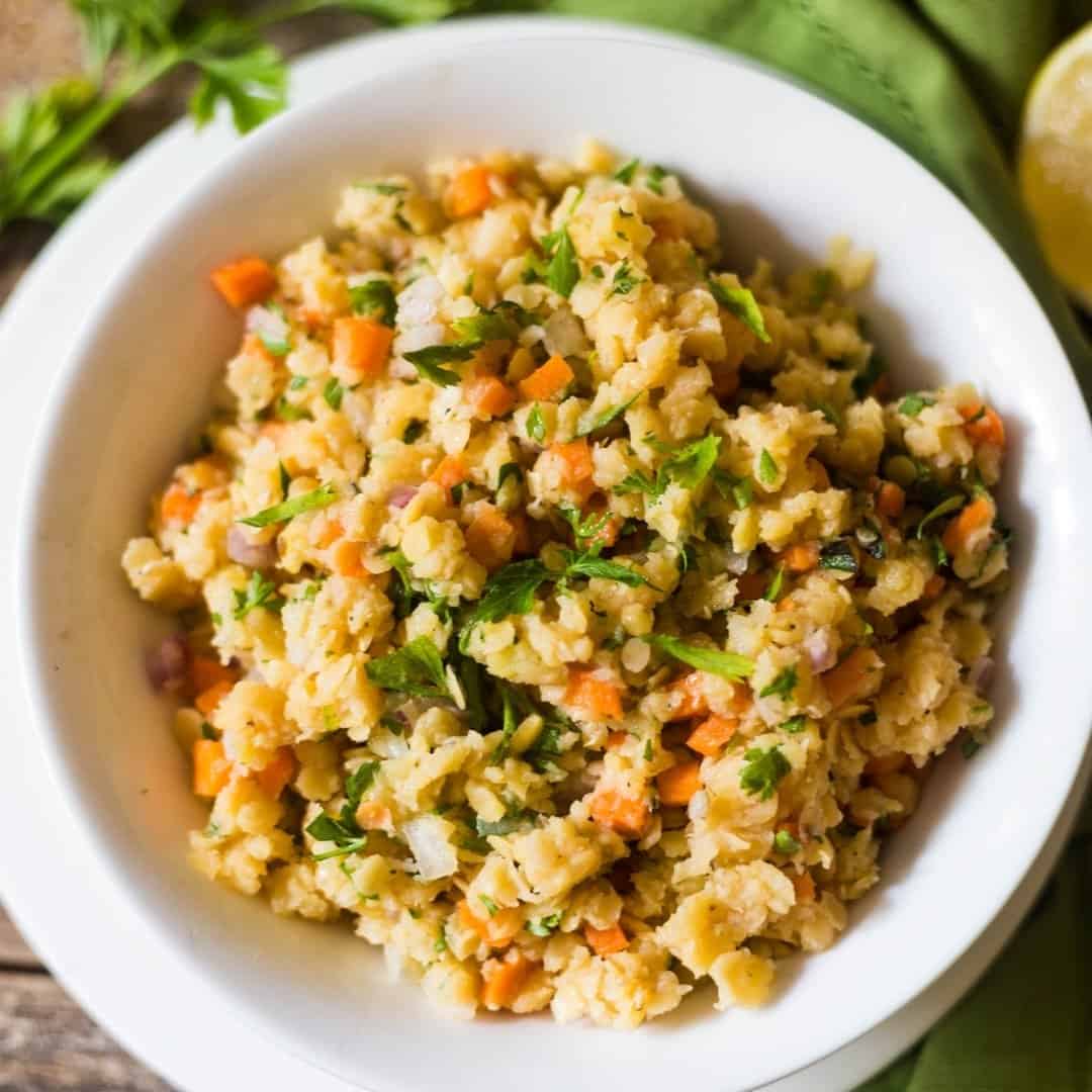 red lentil salad with carrots, celery and fresh herbs in a white salad bowl