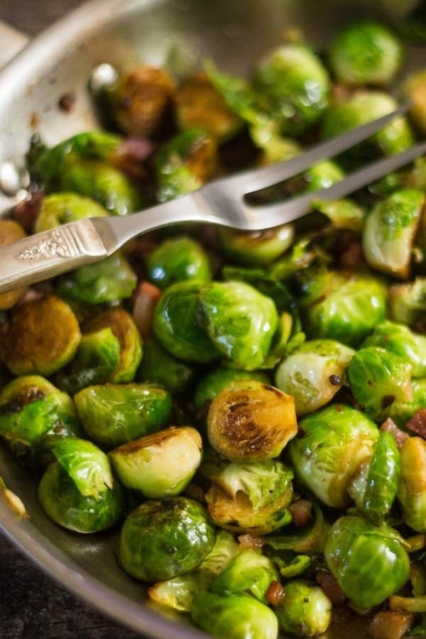 Delicious sauteed Brussels Sprouts and prosciutto in a silver saute pan. Ready to be eaten