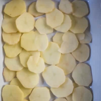 Thinly sliced potatoes in a casserole dish ready to be made into scalloped potatoes