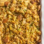 Southern Cornbread Dressing in a white Casserole dish with red linen on the side of the bowl.