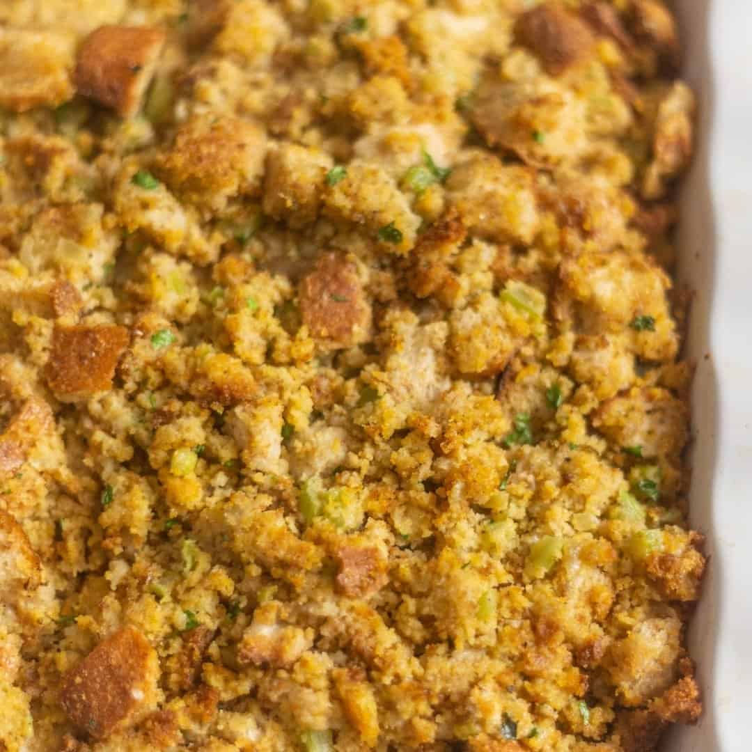 Southern Cornbread Dressing in a white Casserole dish with red linen on the side of the bowl.