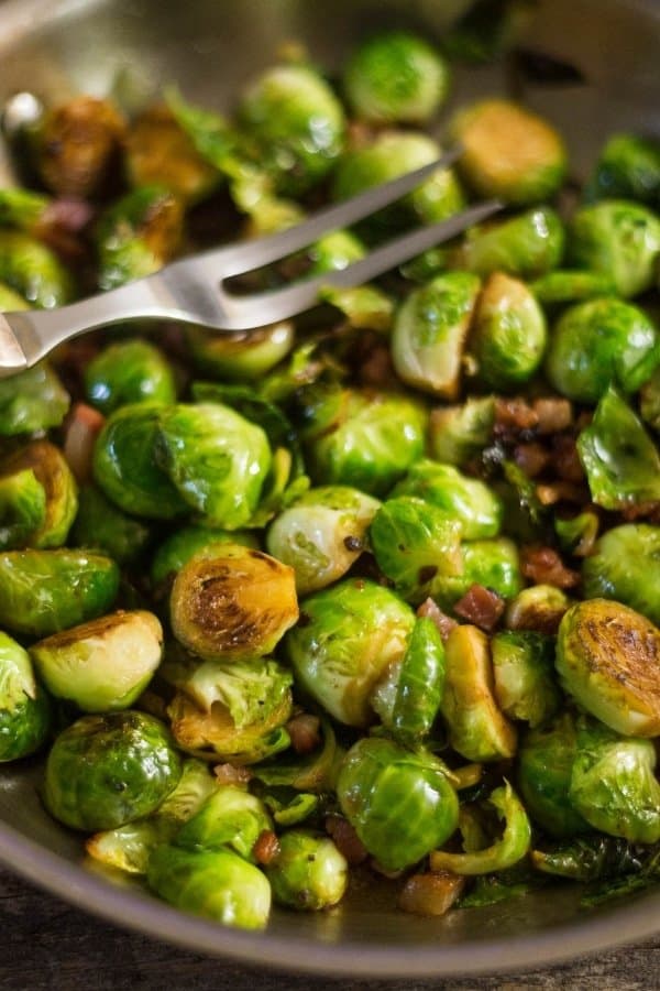 Tasty sauteed Brussels Sprouts with Prosciutto in a large saute pan after being cooked with white wine.