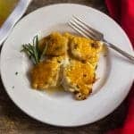 Easy Cheesy Scalloped Potatoes garnished with fresh rosemary on a white plate