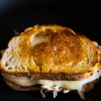 A delicious turkey reuben on a cast iron grill with melting swiss cheese!