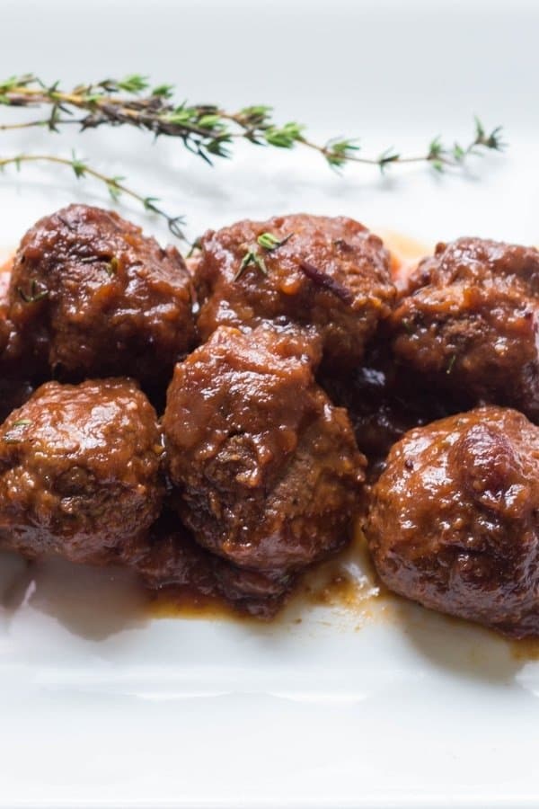 Mouthwatering cranberry meatballs on a platter with fresh thyme ready to be served as an appetizer
