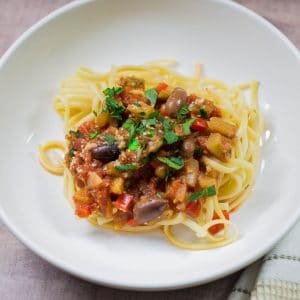 Eggplant pasta served in a white pasta bowl, sprinkled with parsley