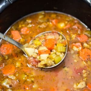 Manhattan Clam Chowder being ladled out of a slow cooker vessel.