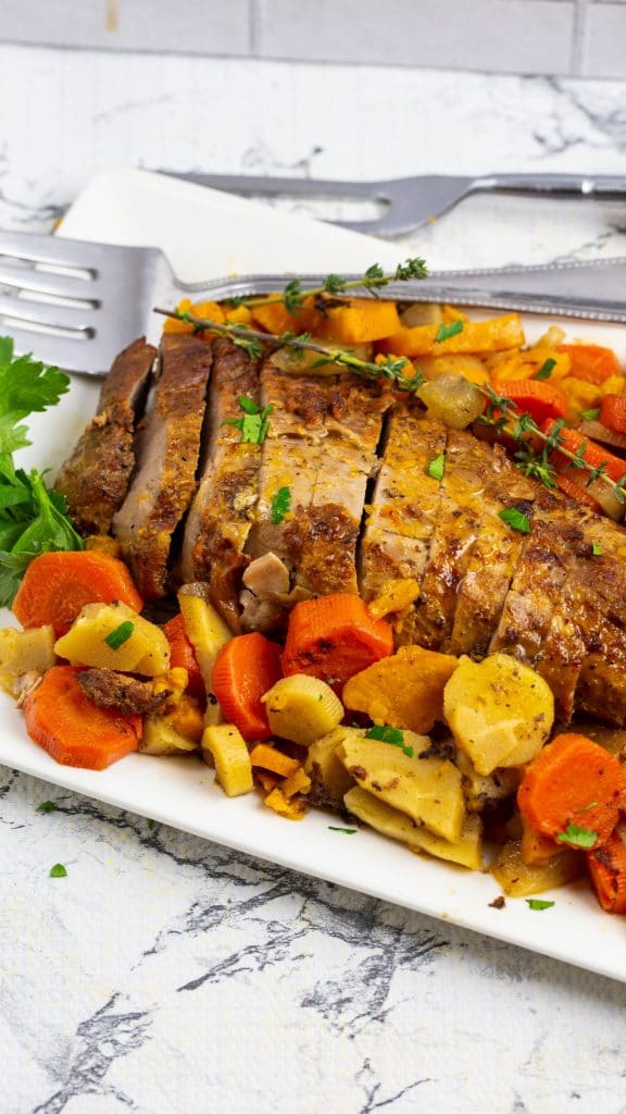 pork tenderloin with root veggies on a white platter