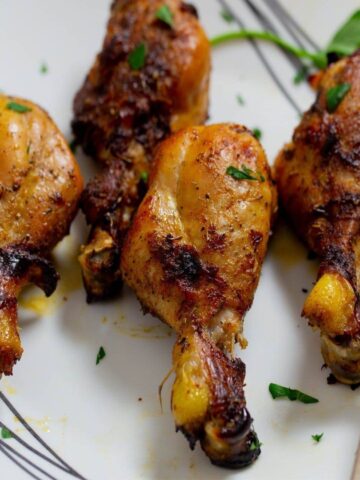 Marinated chicken drumsticks that have been baked on a white platter