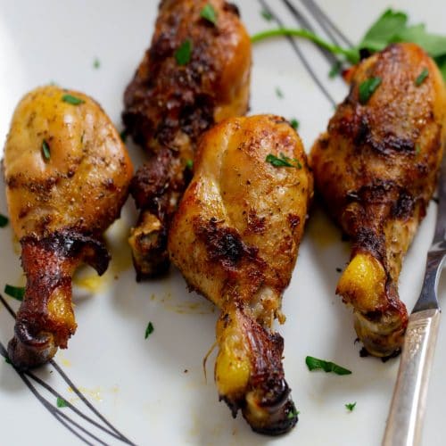 Marinated chicken drumsticks that have been baked on a white platter