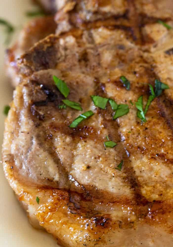 mexican grilled pork chops sprinkled with fresh parsley on a white plate