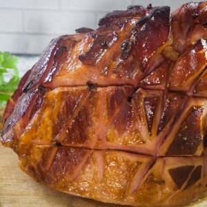 A baked honey glazed ham that has been baked with a glaze and ready to slice.
