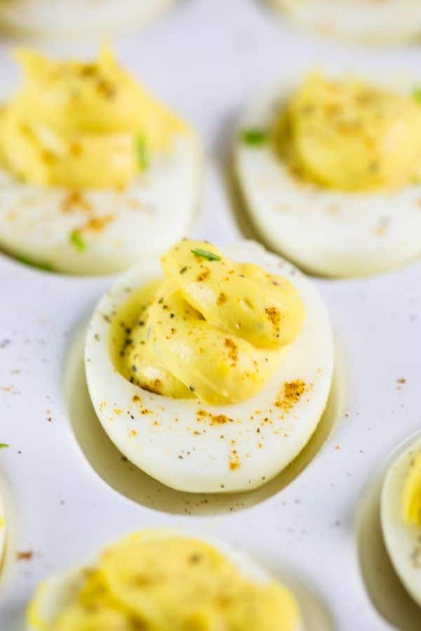 A tray of horseradish deviled eggs on an egg platter sprinkled with black pepper and paprika