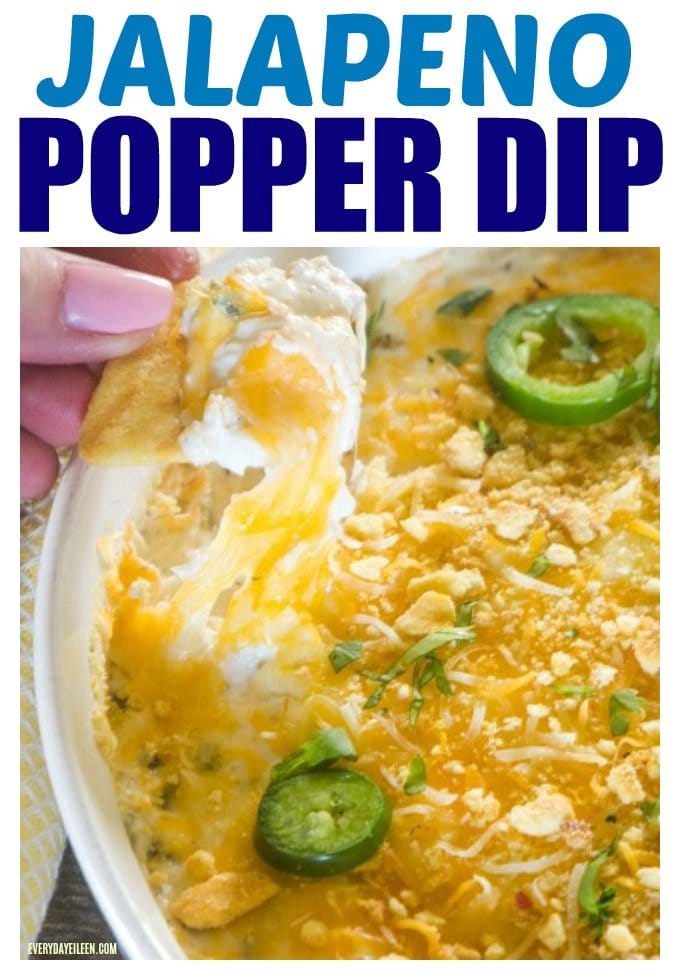 Jalapeno popper dip in a white dip bowl and a chip is being pulled up with melted cheese and popper dip