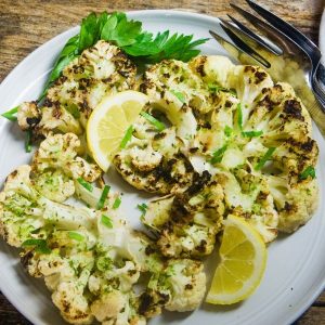 Cauliflower steaks that have been grilled and served on a white plate.